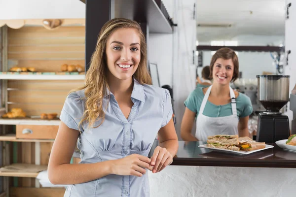 Pretty waitress and customer smiling at camera — Stock Photo, Image