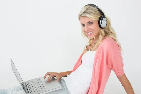 Beautiful woman using laptop while listening to music — Stock Photo, Image