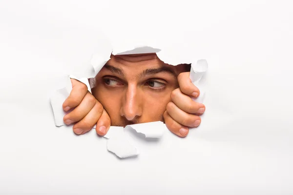 Young man looking through paper rip — Stock Photo, Image