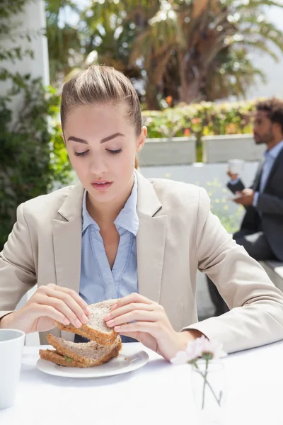 Empresária tendo sanduíche para o almoço — Fotografia de Stock