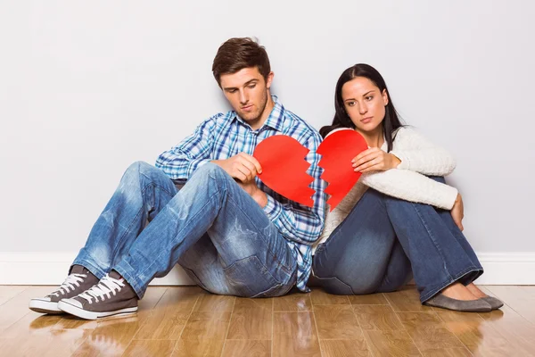 Young couple sitting on floor with broken heart — Stock Photo, Image