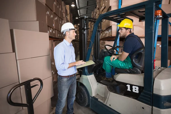 Magazijnbeheerder praten met heftruck chauffeur — Stockfoto