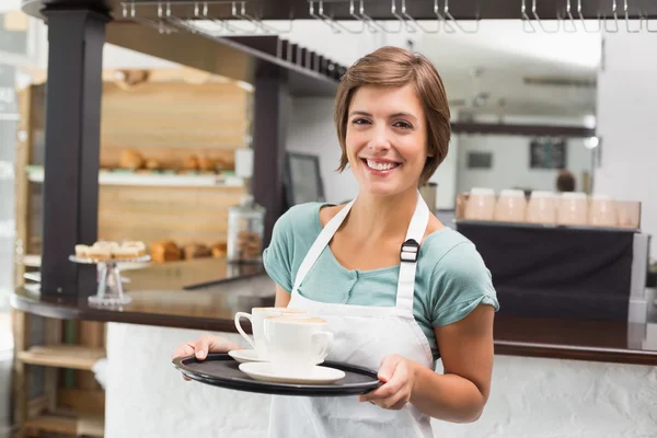 Garson holding tepsi cappuccino ile — Stok fotoğraf