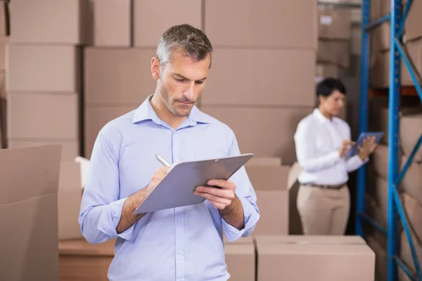 Warehouse manager writing on clipboard — Stock Photo, Image