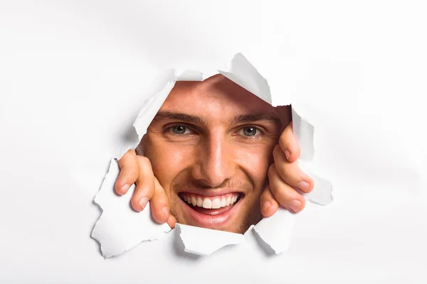 Young man looking through paper rip — Stock Photo, Image