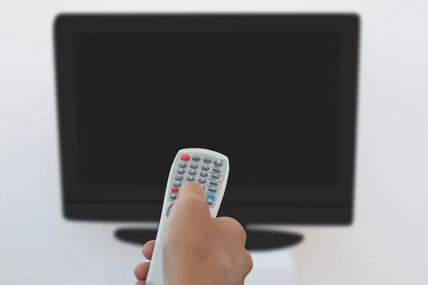 Hand holding remote and changing channel — Stock Photo, Image