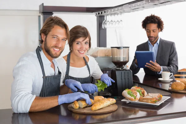 Servidores felizes preparando sanduíches juntos — Fotografia de Stock