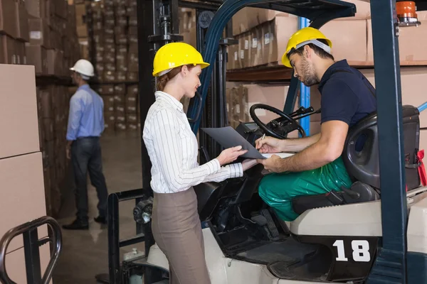 Magazijnbeheerder praten met heftruck chauffeur — Stockfoto