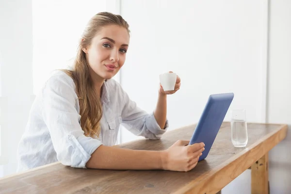 在使用平板电脑时喝咖啡的人的金发美人 — 图库照片
