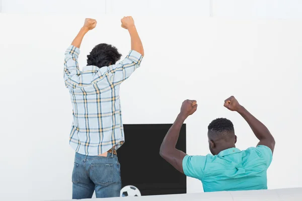 Emocionados aficionados al fútbol animando mientras ven la televisión —  Fotos de Stock