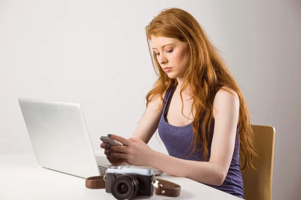 Ziemlich rothaarige Arbeit an Laptop und Kamera — Stockfoto