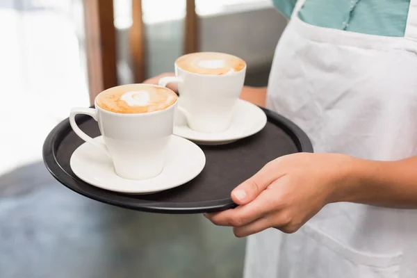 Kellnerin hält Tablett mit Cappuccino — Stockfoto