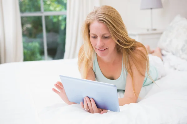 Happy blonde using tablet pc on bed — Stock Photo, Image