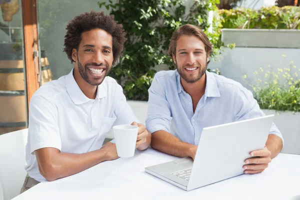 Dos amigos disfrutando del café junto con el ordenador portátil — Foto de Stock