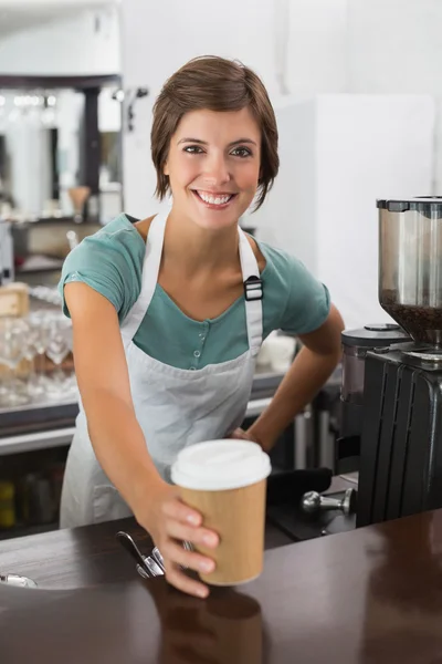 Ganska barista ler mot kameran håller disponibel cup — Stockfoto