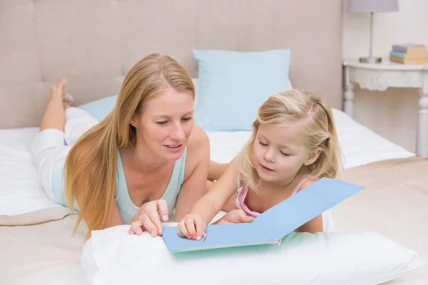 Menina e mãe na cama leitura — Fotografia de Stock