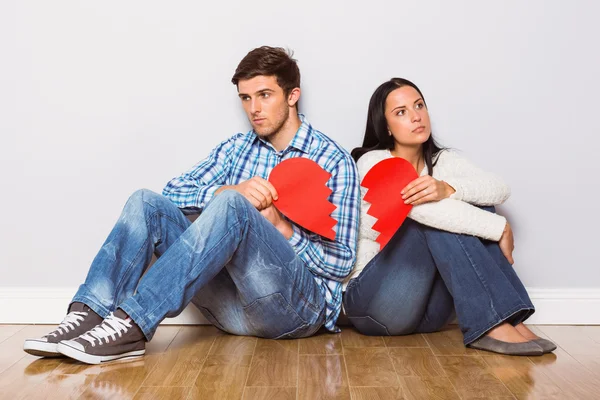 Young couple sitting on floor with broken heart Stock Photo