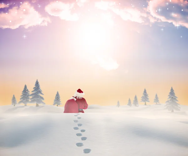 Composite image of santa walking in the snow — Stock Photo, Image