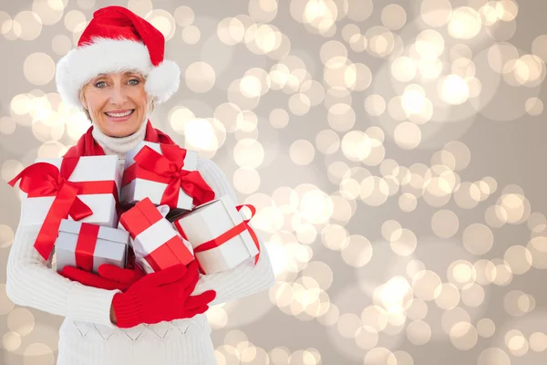 Imagen compuesta de mujer festiva sosteniendo regalos — Foto de Stock