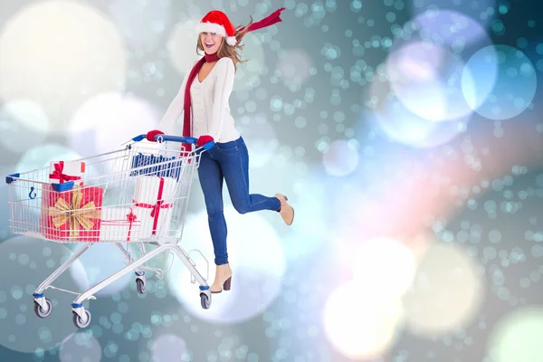 Festive blonde pushing trolley full of gifts — Stock Photo, Image