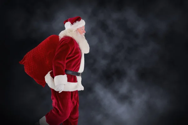 Composite image of santa claus carrying sack — Stock Photo, Image