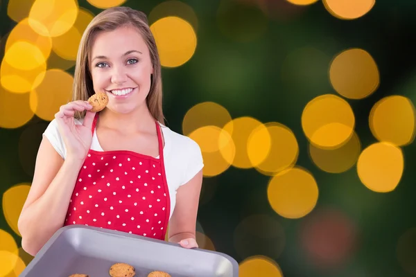 Jolie femme au foyer montrant des cookies chauds — Photo