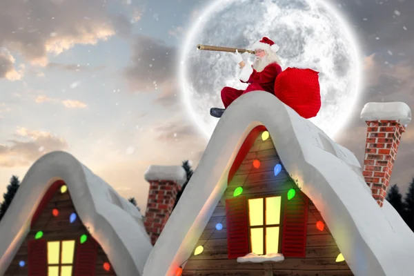 Composite image of santa sitting on roof of cottage — Stock Photo, Image