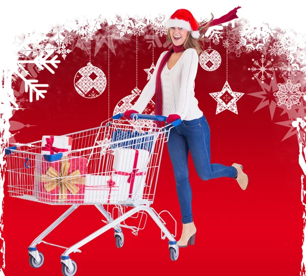 Festive blonde pushing trolley full of gifts — Stock Photo, Image