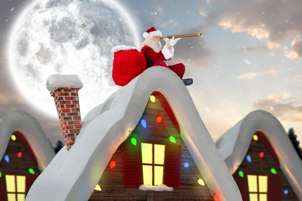 Composite image of santa sitting on roof of cottage — Stock Photo, Image