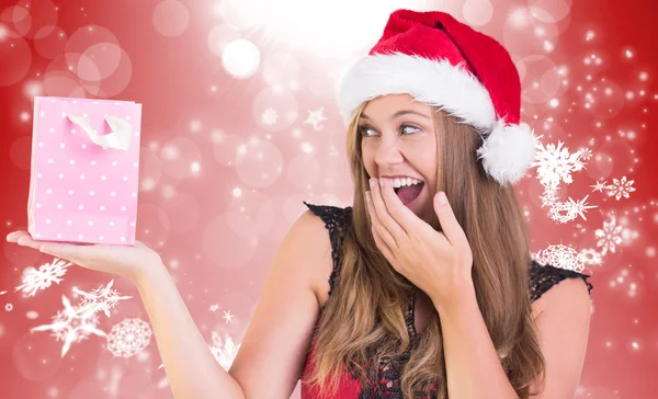 Composite image of festive blonde holding a gift bag Stock Image