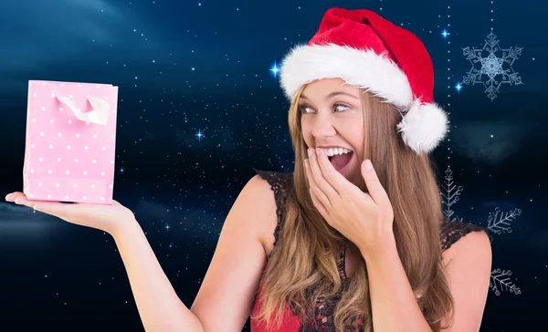 Composite image of festive blonde holding a gift bag Stock Picture