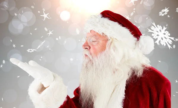 Composite image of santa claus blowing — Stock Photo, Image