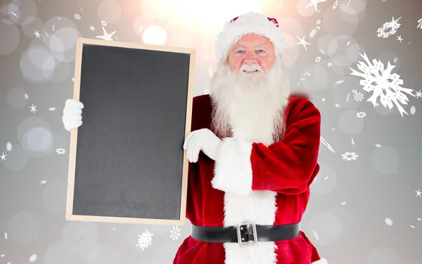 Composite image of santa claus showing blackboard — Stock Photo, Image