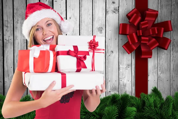 Imagen compuesta de rubia festiva sosteniendo un montón de regalos — Foto de Stock