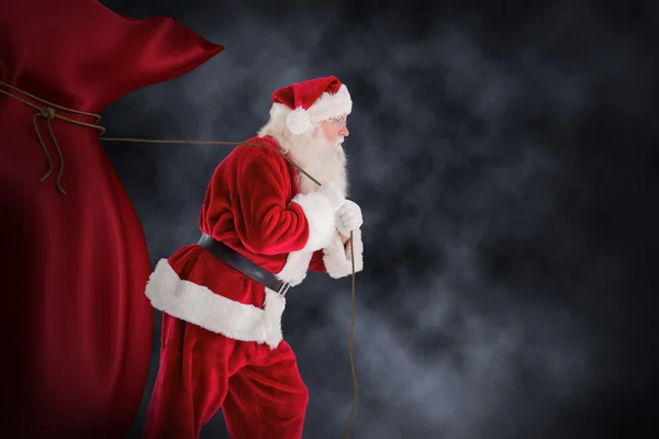 Композитное изображение Санта-Клауса, тянущего канат — стоковое фото