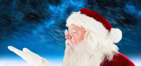 Composite image of santa claus blowing — Stock Photo, Image