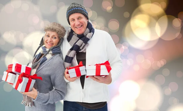 Composite image of festive mature couple holding christmas gifts — Stock Photo, Image