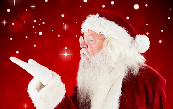 Composite image of santa claus blowing — Stock Photo, Image