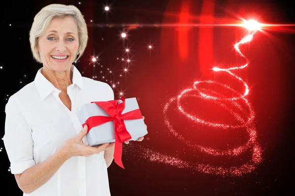 Composite image of mature woman holding gift — Stock Photo, Image