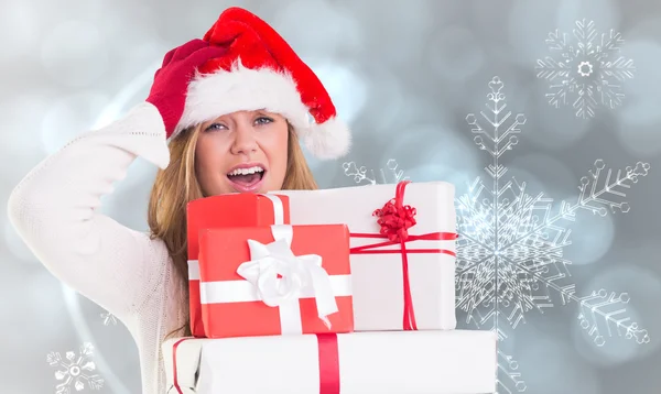 Zusammengesetztes Bild einer festlichen Blondine, die einen Haufen Geschenke in der Hand hält — Stockfoto