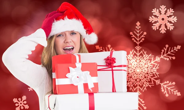 Zusammengesetztes Bild einer festlichen Blondine, die einen Haufen Geschenke in der Hand hält — Stockfoto