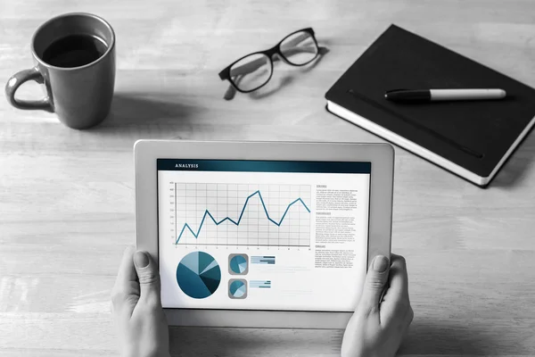 Composite image of businesswoman holding tablet at desk — Stock Photo, Image