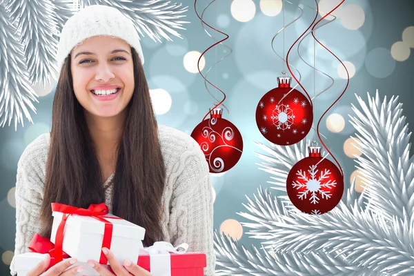 Composite image of festive brunette holding gifts — Stock Photo, Image