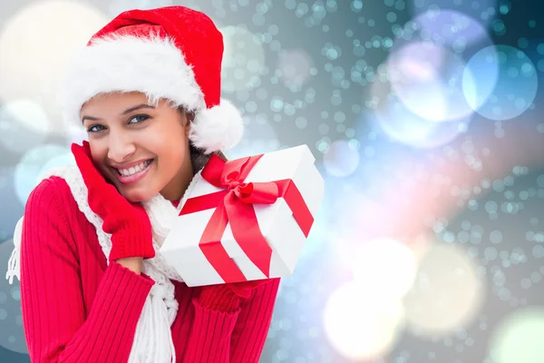 Composite image of festive brunette holding gift — Stock Photo, Image