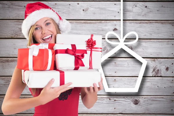 Composite image of festive blonde holding pile of gifts — Stock Photo, Image