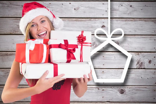 Imagen compuesta de rubia festiva sosteniendo un montón de regalos — Foto de Stock