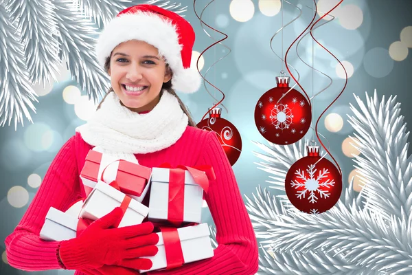 Composite image of festive brunette holding gifts — Stock Photo, Image