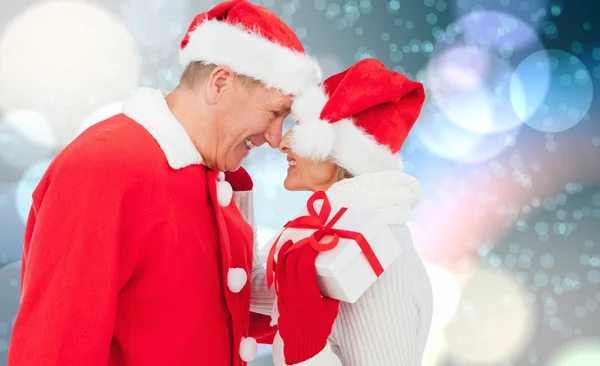 Composite image of festive mature couple holding gift — Stock Photo, Image