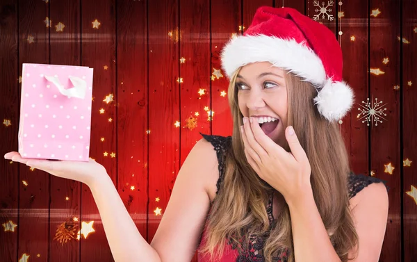 Zusammengesetztes Bild einer festlichen Blondine mit einer Geschenktüte — Stockfoto