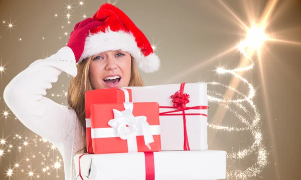 Zusammengesetztes Bild einer festlichen Blondine, die einen Haufen Geschenke in der Hand hält — Stockfoto